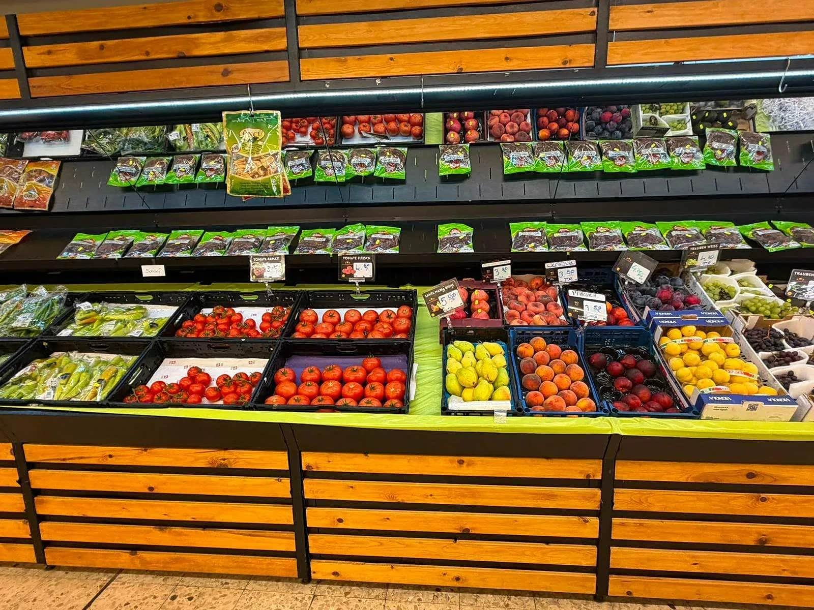 Fruit and vegetable shelf with tomatoes, peppers and oranges at Ali Supermarkt
