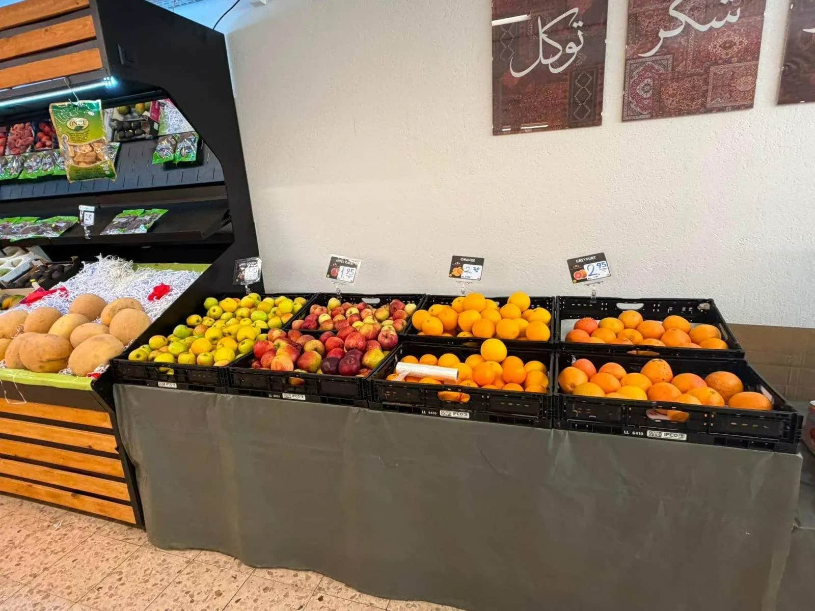 Obstauslage mit Orangen, Äpfeln und Melonen